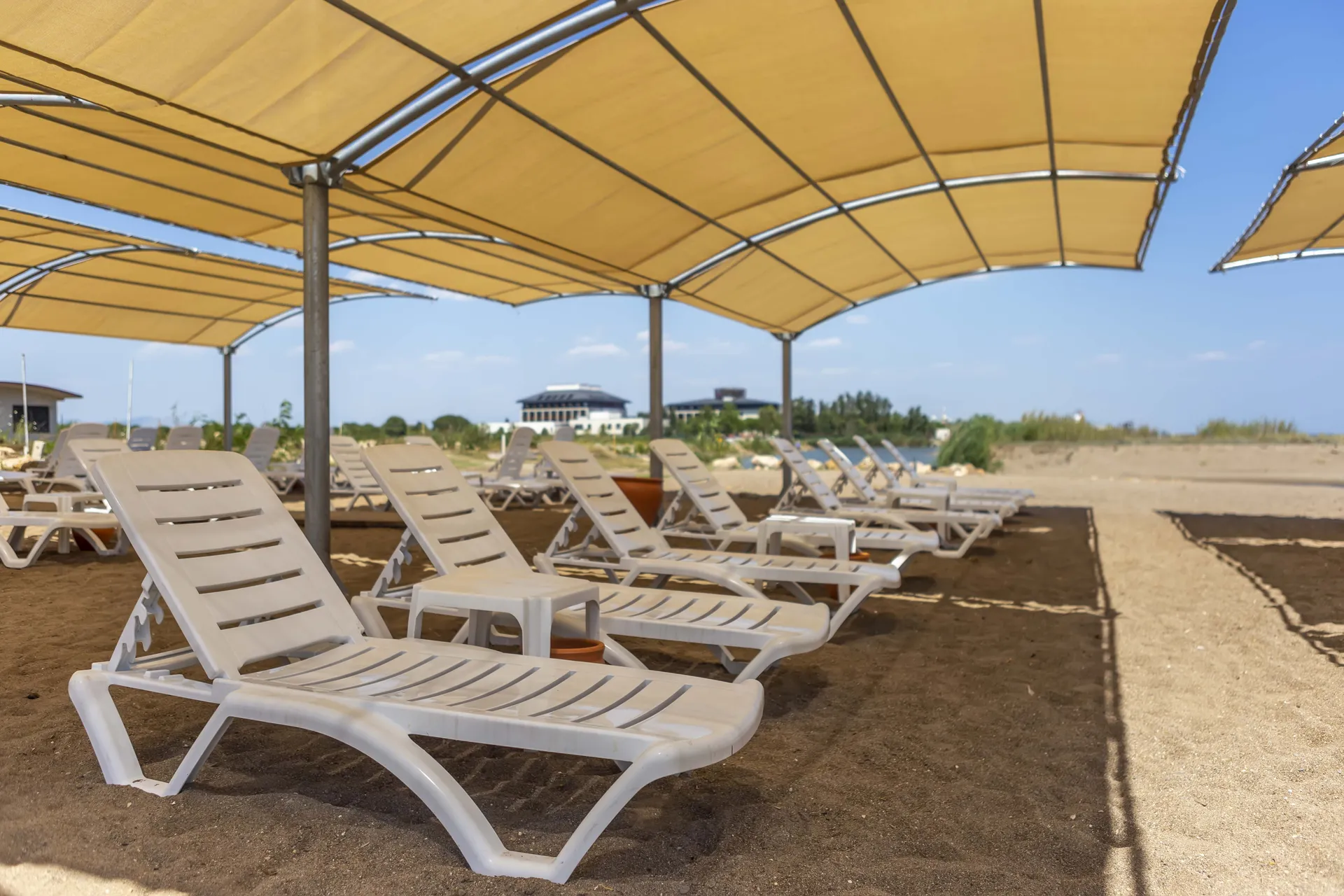 Solena Lara Hotel plaj alanında gölgelikler altında sıralanan şezlonglar